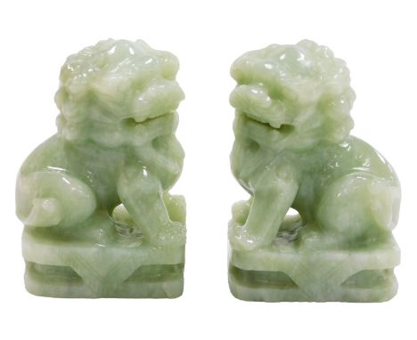 A pair of Chinese celadon jade dogs of fo, modelled seated on a rectangular base, 14cm high.
