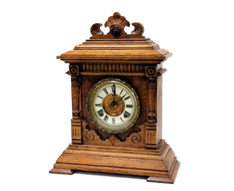 A late 19thC oak cased mantel clock, circular brass dial with enamel chapter ring bearing Roman numerals, Ansonia eight day m
