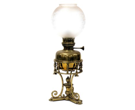 A Victorian brass oil lamp, with a brass gallery, raised on scrolling supports and a triform base, with an etched glass shade
