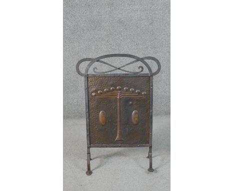 A Victorian Arts &amp; Crafts planished copper fire screen, in a riveted wrought iron frame with Celtic design top, on spade 