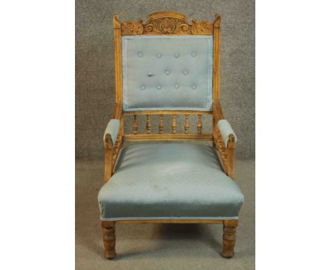 A late 19th century walnut armchair, with a carved top rail, upholstered to the arms, seat and buttoned back in light blue fa
