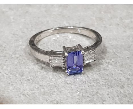 Ladies 9ct white gold tanzanite + diamond ring , featuring a emerald cut tanzanite set in the centre with 2 baguette diamonds