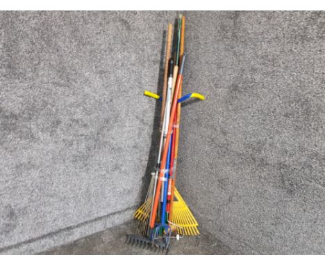 A bundle of garden tools to include rakes and a hoe.