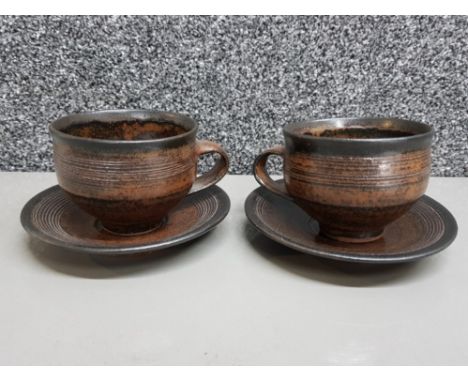 A good pair of cups and saucers by Gwyn Hanssen Pigott in rich Tenmoku glaze with impressed mark