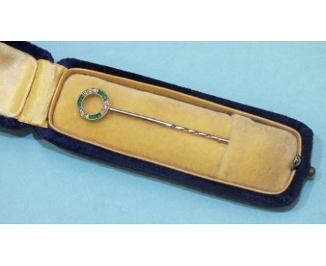 An Edwardian stick pin in the form of a circlet set alternate triplets of square cut emeralds and 8/8 cut diamonds in white m