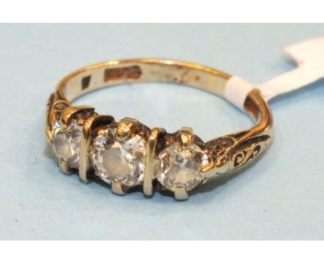 A three stone diamond ring claw set three old brilliant cut diamonds between carved shoulders on 18ct gold mount, size K, 3.3