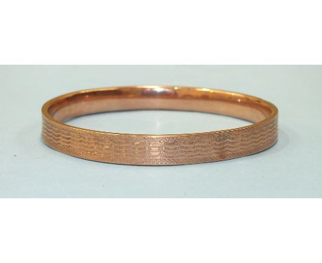 A 9ct rose gold slave bangle with engine turned engraving, 15.2g (af - dented).