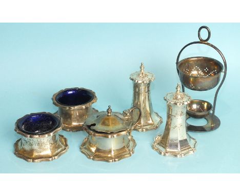 A circular cruet set, comprising 2 peppers, 2 salts and a mustard with blue glass liners, Birmingham 1922 and a tea strainer 