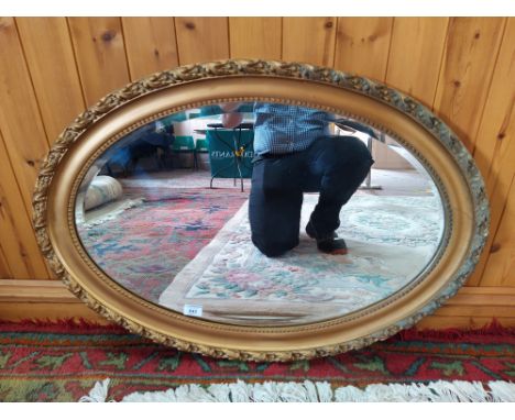 An Edwardian gilded oval wall mirror with bevelled glass