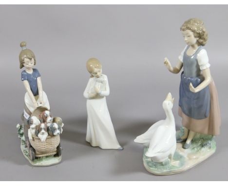 A Lladro figure of a girl pushing a pram along with two Nao figurines.