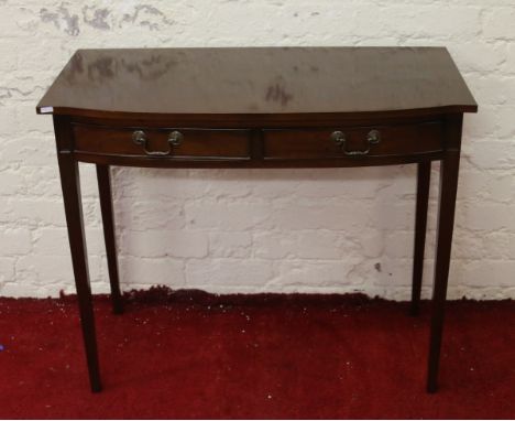 A two drawer mahogany side table raised on tapering supports.