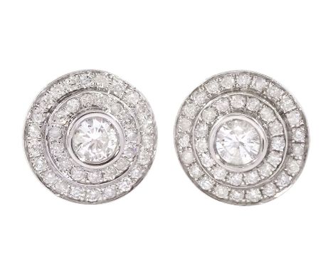 Pair of 18ct white gold round brilliant cut diamond halo stud earrings, the central bezel set diamonds with two row diamond s