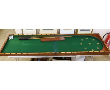 A Victorian folding cased bagatelle board, green baize interior with markers and two cues, 223.5cm open