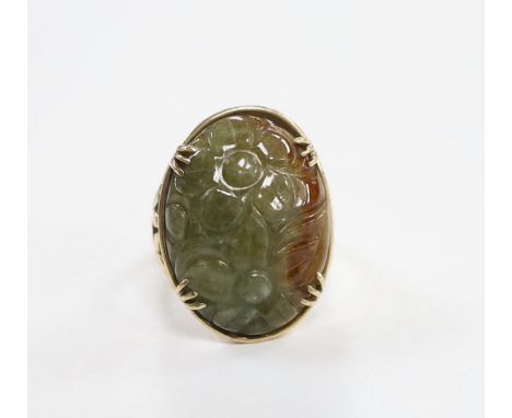 A 14k yellow metal and foliate carved oval cabochon jade set ring, size L, gross weight 7.3 grams.