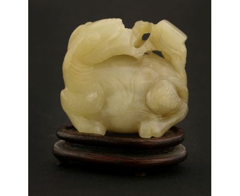 A Chinese jade carving, late Qing dynasty, of a recumbent mythical beast, its head turned to its back with a branch in his mo