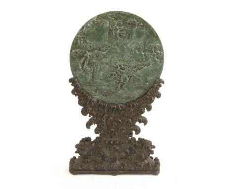 A Chinese jade plaque, of circular form, carved with a scholar and attendants under pine trees, greeting a friend on a buffal