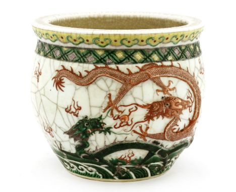 A Chinese wucai planter,19th century, decorated with dragons chasing a flaming pearl in relief above waves, the reverse with 