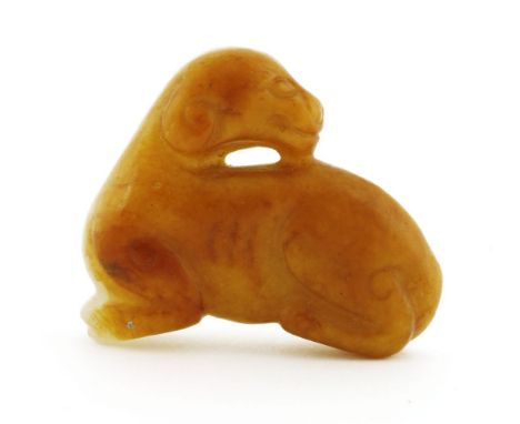 A Chinese jade carving,Ming dynasty (1368-1644), of a recumbent dog with his head turned back, the stone of a white tone with