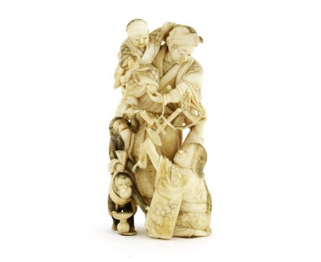 A Japanese ivory okimono,Meiji period (1868-1912), of a samurai holding a boy in his arms, a lady kneeled at his feet with a 