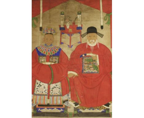 A large Chinese ancestor portrait painting,early 20th century, of an old couple seated on armchairs in front of a table with 