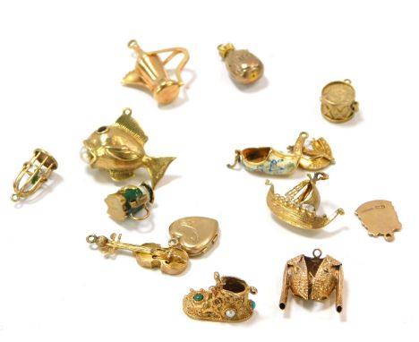 A group of 9ct gold charms, comprising fish with pearl, money bag, bird cage, ship, drum, bullfighting suit, jug, two shoes, 