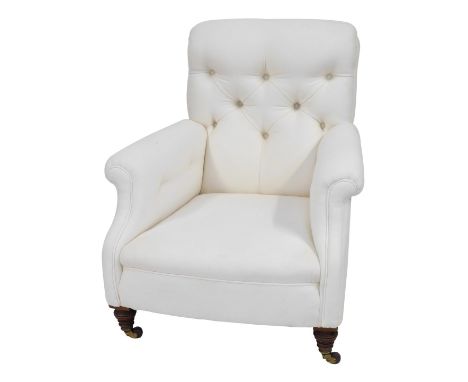 A Victorian button back low armchair, deep seated with turned walnut legs with brass and ceramic castors, upholstered in crea