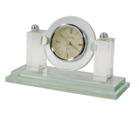 A Lloyd quartz mantel clock, with 6cm diameter, Roman numeric face, flanked by brass columns on a stepped rectangular base.