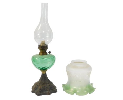 An early 20thC oil lamp, with frosted, clear and green glass shade, textured green glass reservoir and metal stem, with plain
