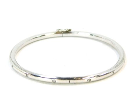 An 18ct white gold diamond set hinged bangle, set with fourteen tiny diamonds, safety clip clasp, 6cm diameter, 9g all in.