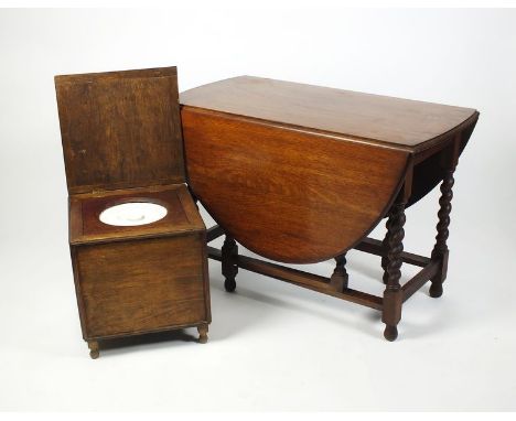 A 1930s Carolean style oak drop-leaf dining table with oval bevel top raised on barley twist and block legs, single gate leg 