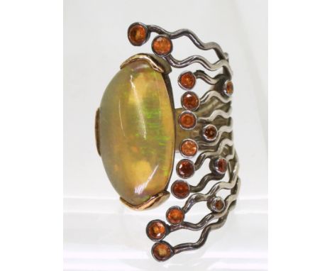 A yellow and white metal handmade bespoke designer ring, set with a large colourful jelly opal and orange sapphires. Stamped 