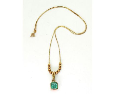 An emerald pendant and chain with bead detail. The step cut emerald is approx 7.7mm x 7.5mm x 4.3mm, length of 18ct gold chai