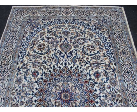 A 20th century Persian Nain carpet, woven with a bold central medallion on a busy foliate field, predominately cream/blue gro