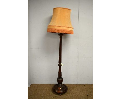 A substantial carved and stained beech standard lamp, with fluted and leaf carved column, beaded circular base, with tasselle