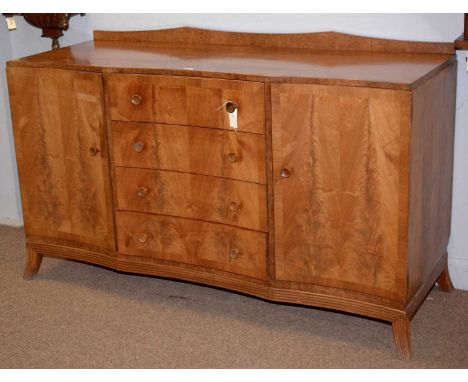 A mid 20th Century banded light mahogany sideboard, with shaped front, fitted four central short drawers (the top drawer fitt