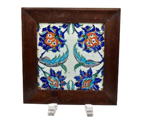 AN ‘ISNIK’ POTTERY TILE, 19TH CENTURYDepicting four stylised flower heads, the reverse unglazed, pine frameThe tile: 25cm by 