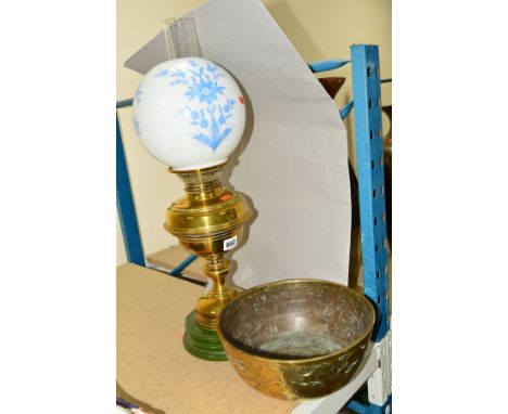 A VICTORIAN STYLE OIL LAMP having a brass body over a green ceramic base, complete with chimney and shade decorated with blue