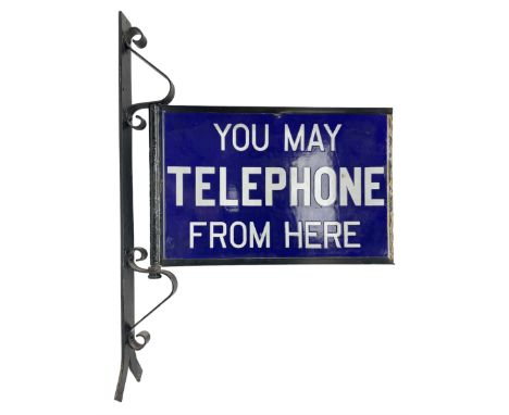 Double sided enamel sign, inscribed 'You may telephone from here' upon a hinged wrought-iron bracket, H72cm, L50cm