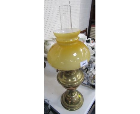 A 20thC brass oil lamp, on brass stem with a yellow glass shade and chimney.