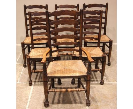 A set of six George III type oak ladder back country chairs, 20th century, each chair with shaped rungs over an envelope rush