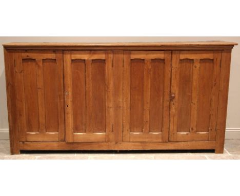 A large Victorian pitch pine ecclesiastical hall cupboard, formed with two pairs of panelled cupboard doors, each opening to 