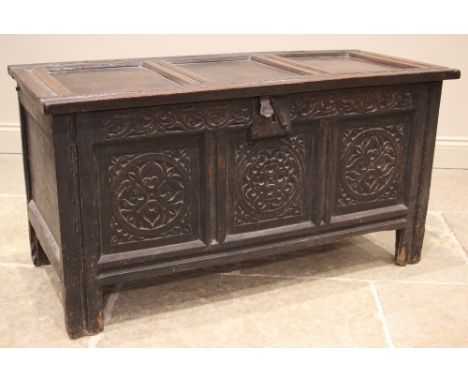 An early 18th century oak coffer, the three panel cover on hook and eye hinges opening to a fitted candle box, above a carved