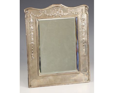 An Edwardian silver mounted mirror, William Neale, Chester 1908, the rectangular frame with embossed garland and bow decorati