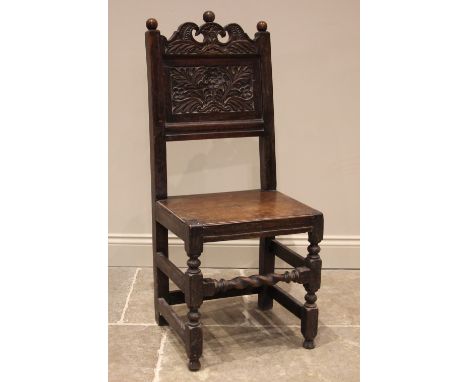 A 17th century oak back stool, probably Lancashire, the three spherical finials over a scrolled crest and a foliate carved ba