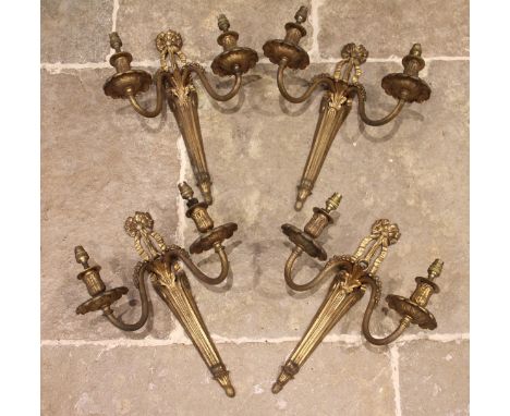 A set of four gilt metal two branch wall light sconces, mid 20th century, cast with a ribbon tied crest over acanthus cast ba
