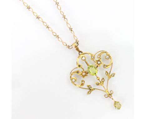 An Edwardian peridot coloured pendant, the oval cut stone set within a sinuous designed openwork mount with seed pearl set de