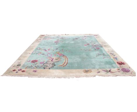 A very large Chinese wool carpet, the central green field adorned with exotic birds upon flowering branches and a rocky outcr