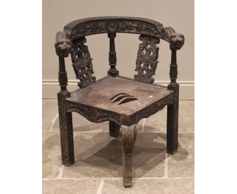 A Victorian carved oak corner chair, the curved top rail extending to lion mask terminals above the board seat, over a foliat