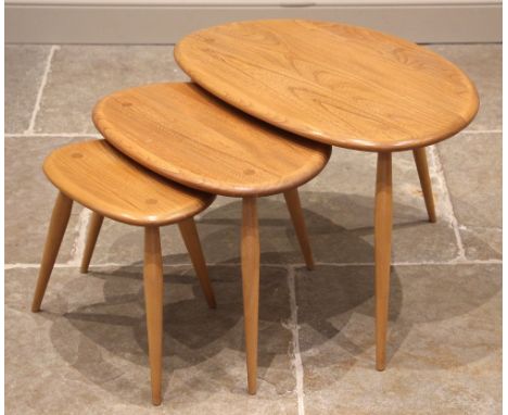An Ercol nest of three blonde elm and beech pebble tables, late 20th century, the rounded table tops upon tapering splayed le
