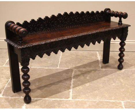 A Victorian carved oak window/hall seat, the shaped back rest carved with recurring flowerheads, extending to bobbin turned h